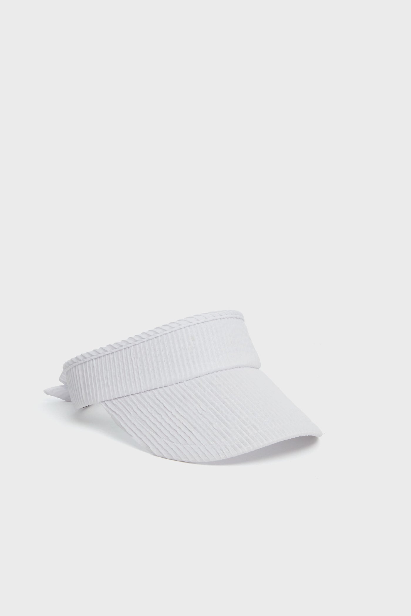 A sleek Lele Sadoughi white ribbed visor cap, crafted from a ruched poly blend for comfort and style, featuring an adjustable back strap.