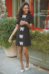 Young woman in a classic, high-end Beaded Bows Bernadette Mini Dress, featuring sparkly bow details, embodying an effortless, fun, and confident style.