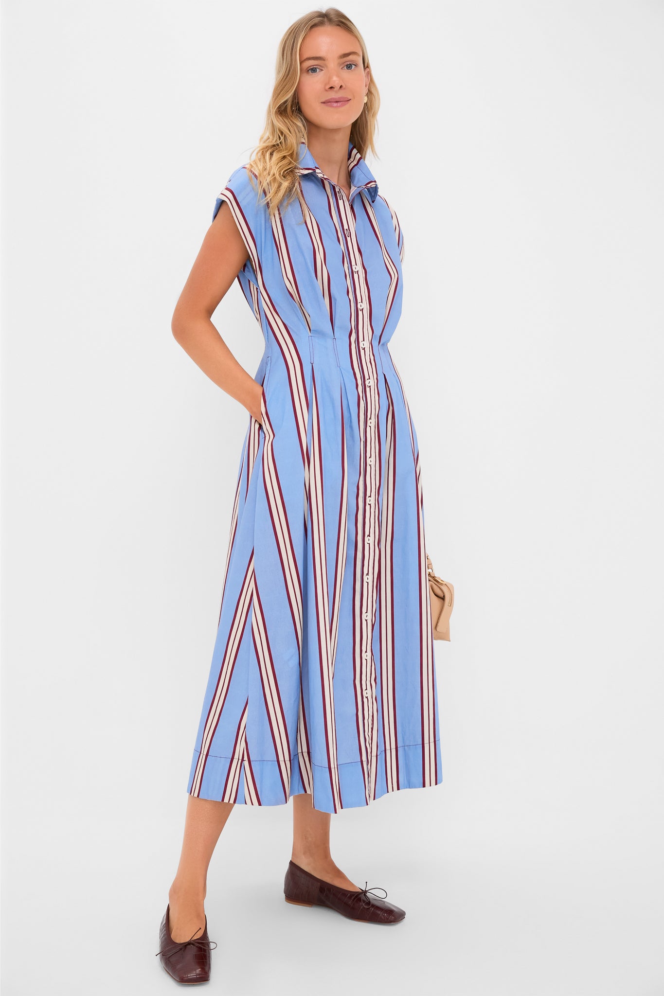 Model in Striped Mirante Shirt Dress: an ankle-length, effortless classic with bold stripes and side pockets. Styled with ballet flats and a handbag for a high-end, fun look.