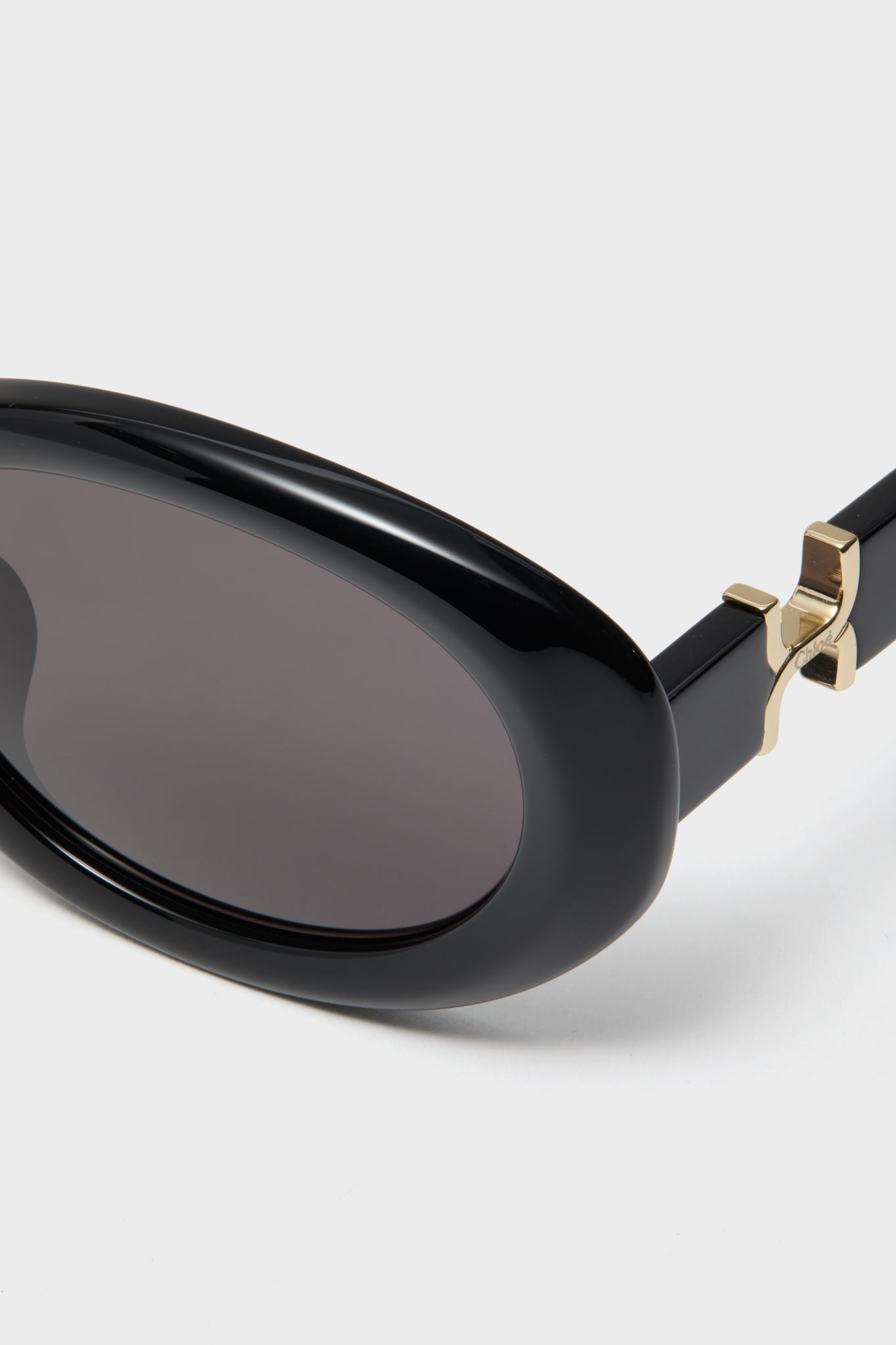 Shiny Solid Black Marcie Sunglasses with glossy oval frame, dark lenses, and gold-tone hinge, embodying classic, effortless, and fun style with a high-end touch.