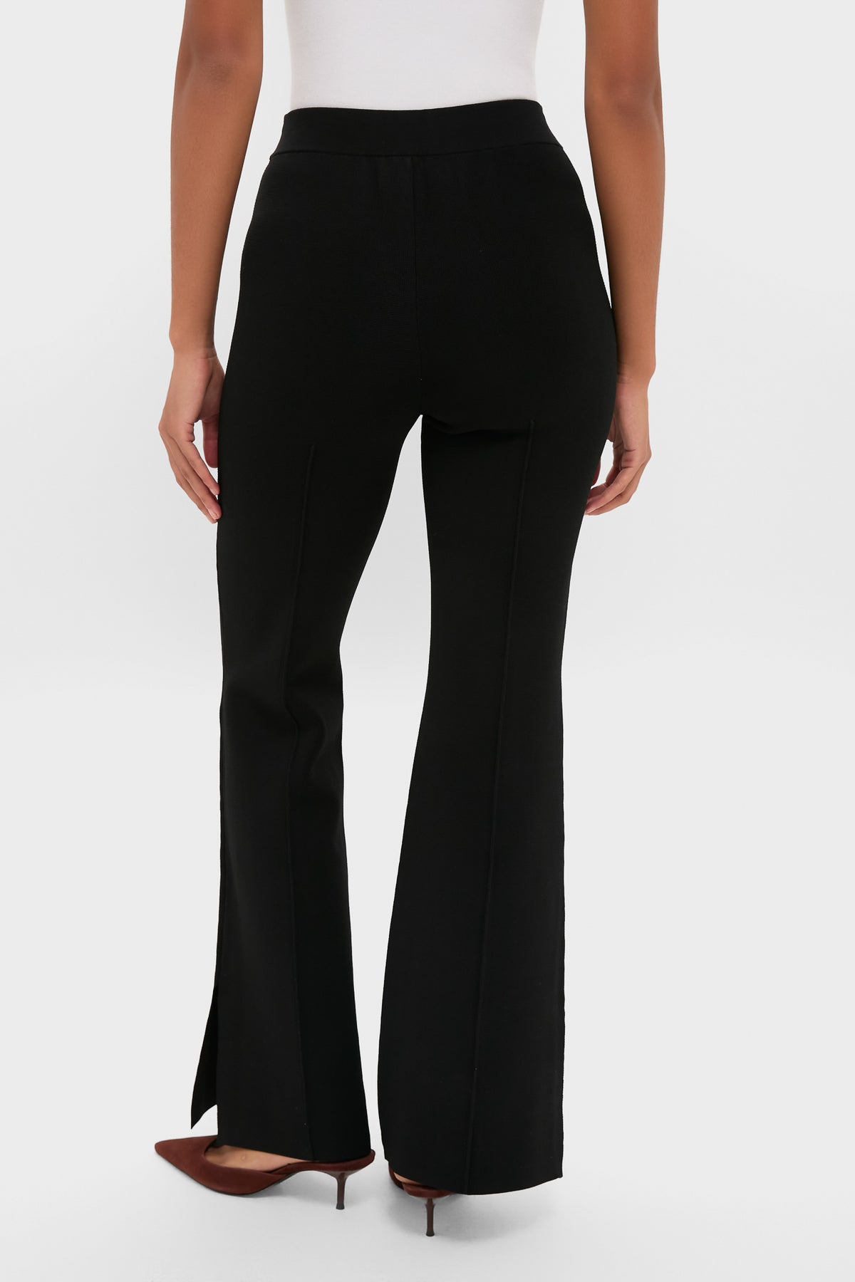 Black Hana Pull On Full Flare trousers with a classic flare-leg design, subtle center seam, and side vents, styled effortlessly with dark brown mid-heel pumps.