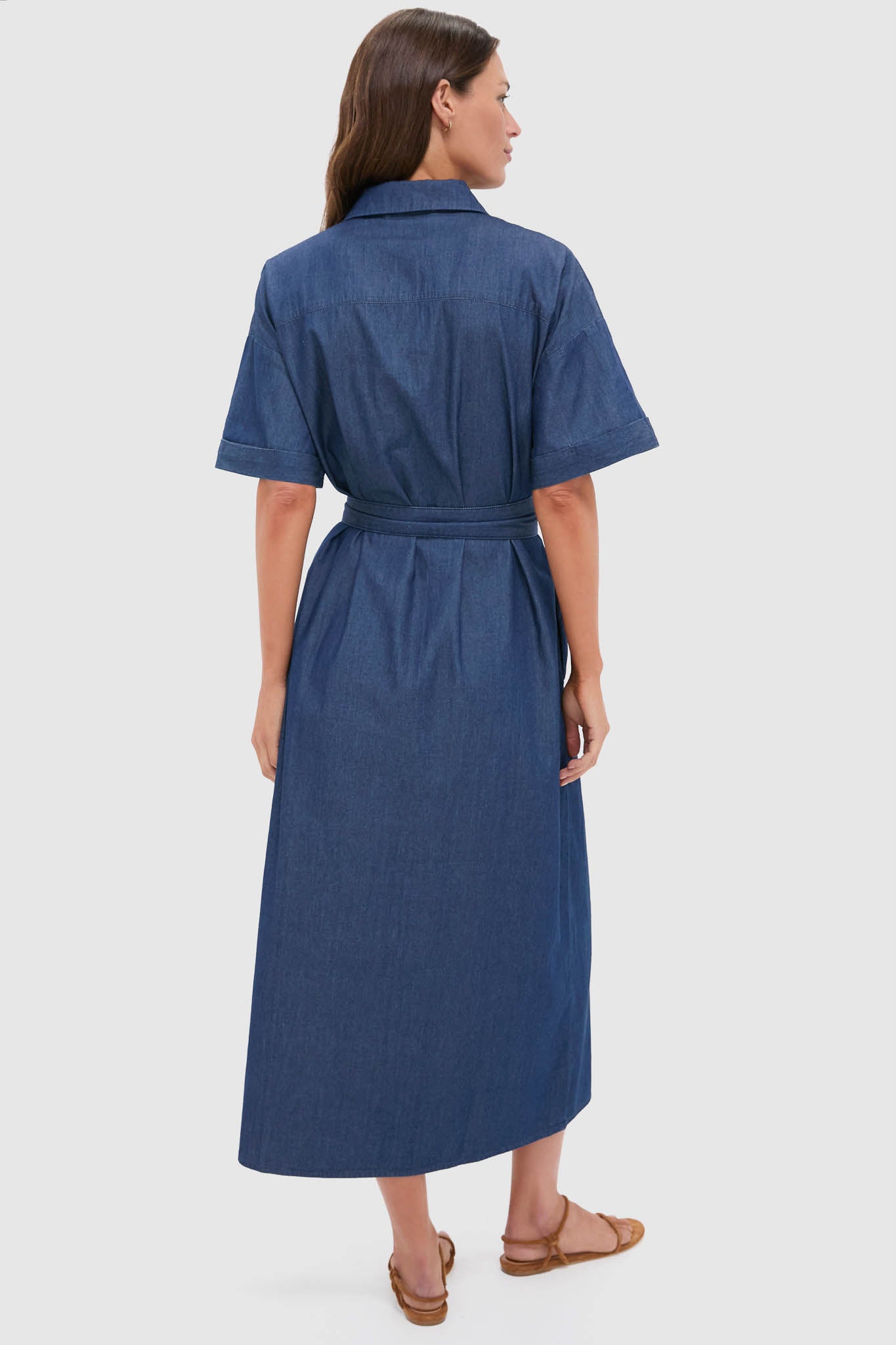 Model in a classic Dark Denim Zacara Dress, featuring an effortless self-tie belt, drop shoulders, and short sleeves, paired with fun, high-end strappy sandals.