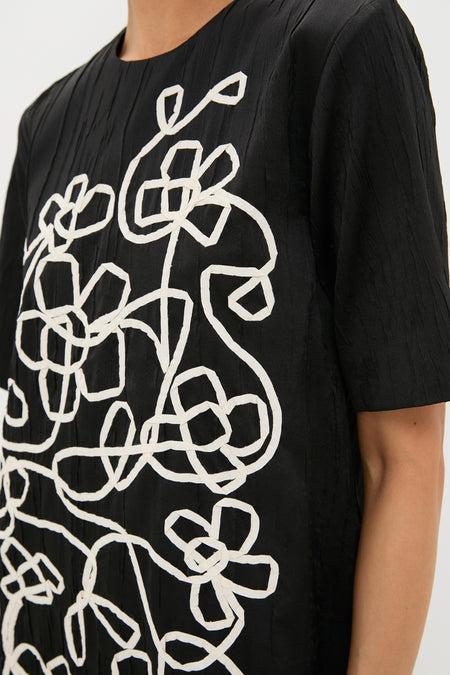 Model wearing the Onyx and Ivory Classic Katya Mini Dress, showcasing an effortless, high-end design with fun, abstract floral embroidery across the front.