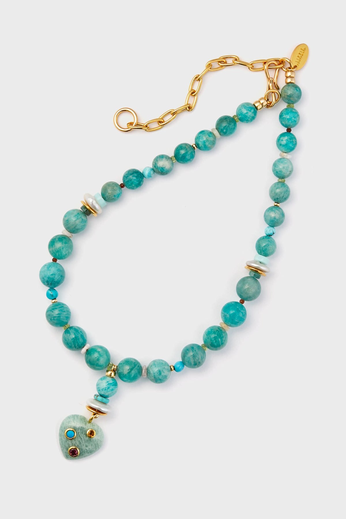 The Lizzie Fortunato handcrafted beaded necklace showcases turquoise beads, a gold chain with spacers, and a heart pendant embellished with three small colorful stones.