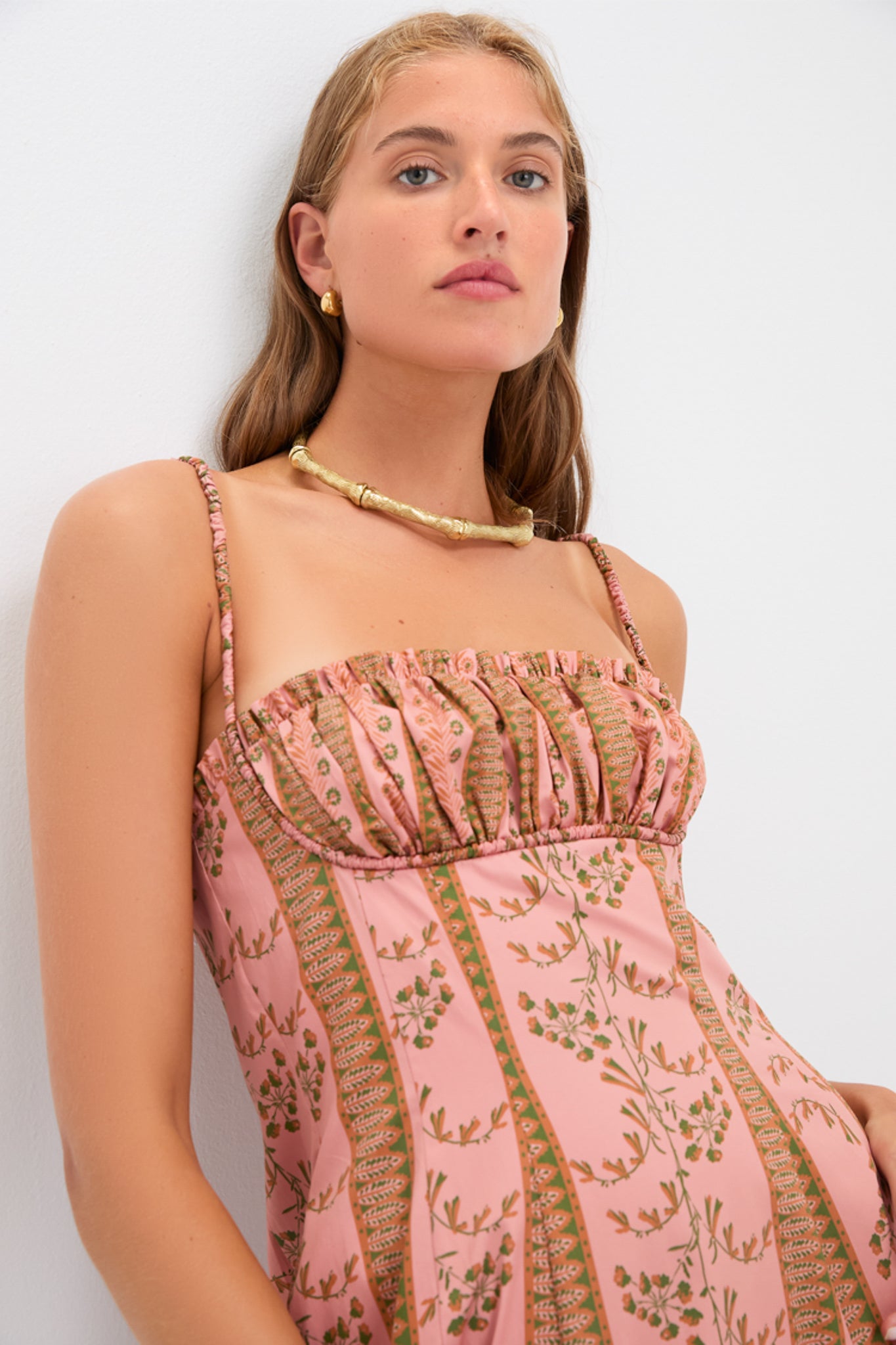 Young woman wearing the classic Rust Dandelion Floral Stripe Maisie Dress, featuring effortless spaghetti straps and a fun, high-end floral design, accessorized with gold-tone jewelry.