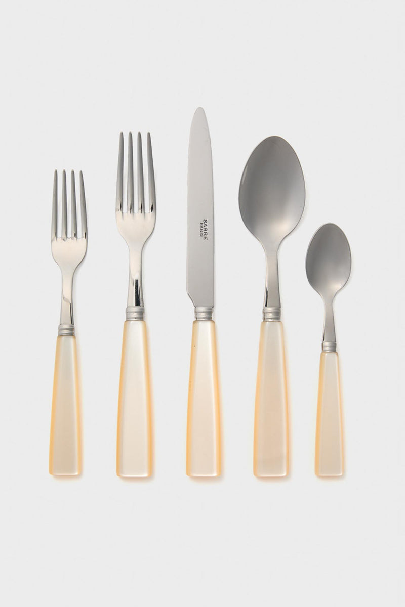 A Sabre Paris 5-piece place setting includes stainless steel cutlery with cream handles: two forks, a knife, a tablespoon, and a teaspoon—all arranged side by side.
