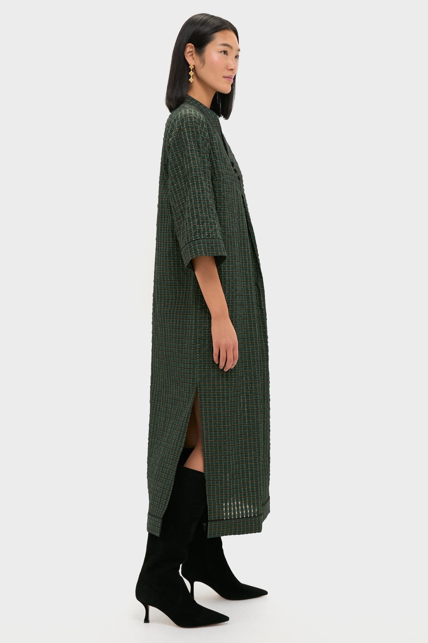Model wearing the classic, high-end Metallic Green Plaid Indy Maxi Dress, effortlessly styled with black suede boots and gold earrings, showcasing a fun, relaxed elegance.
