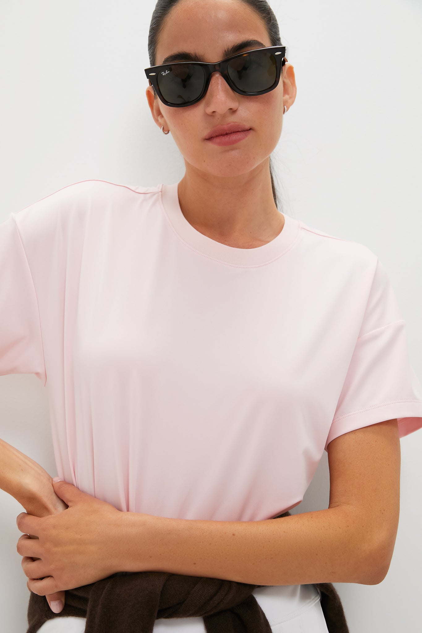 Person wearing classic Pink Short Sleeve Performance Jersey Ryan Boyfriend Tee, exuding effortless style with sunglasses and sweater tied at waist, embodying fun, high-end Tuckernuck spirit.