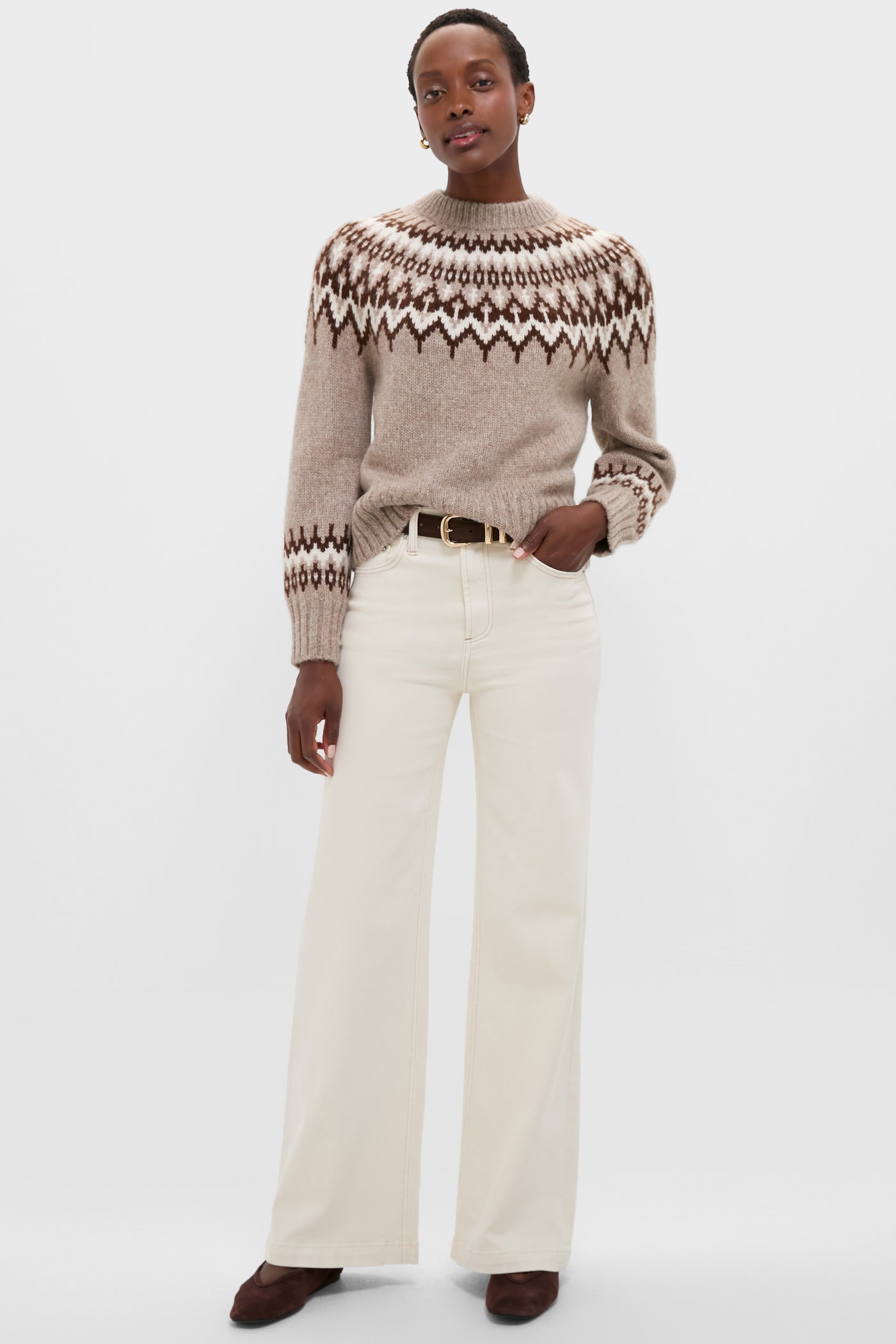 Model wearing the Taupe Fairisle Thatcher Crewneck, a classic, effortless alpaca blend sweater with a Nordic pattern, styled with high-waisted jeans and suede shoes.