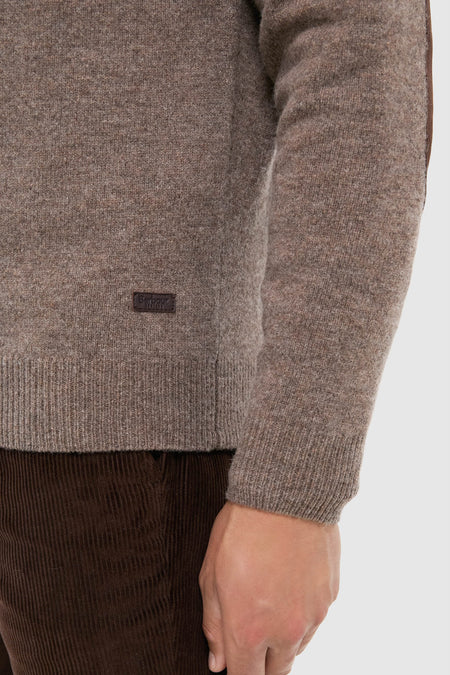 Person wearing the Dark Stone Essential Patch Half Zip Knitted Jumper with leather elbow patches, exuding a classic, effortless style. Paired with dark corduroy trousers, embodying high-end, fun fashion.