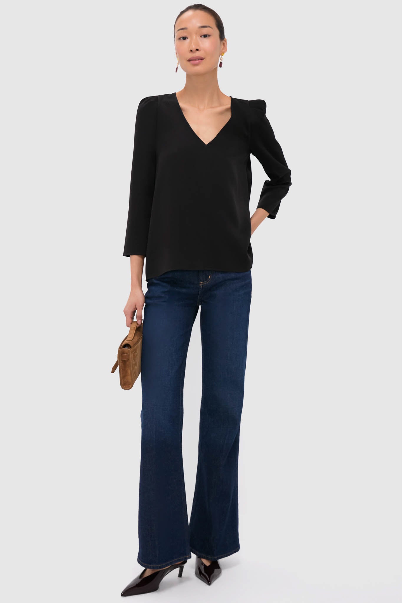 Model showcases an effortless, classic style with the Wine Allie Earrings, featuring colorful stones in sparkling drops, alongside a black blouse and dark indigo jeans.