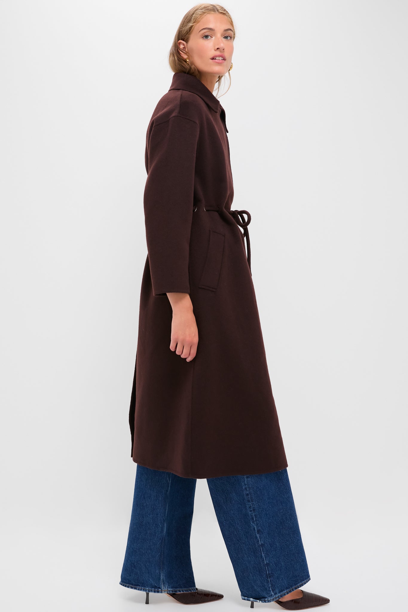 Model in profile wears the classic Chocolate Kate Coat, showcasing an effortless, high-end style. The coat features a wide V-collar and drawstring waist, embodying Tuckernuck's fun elegance.