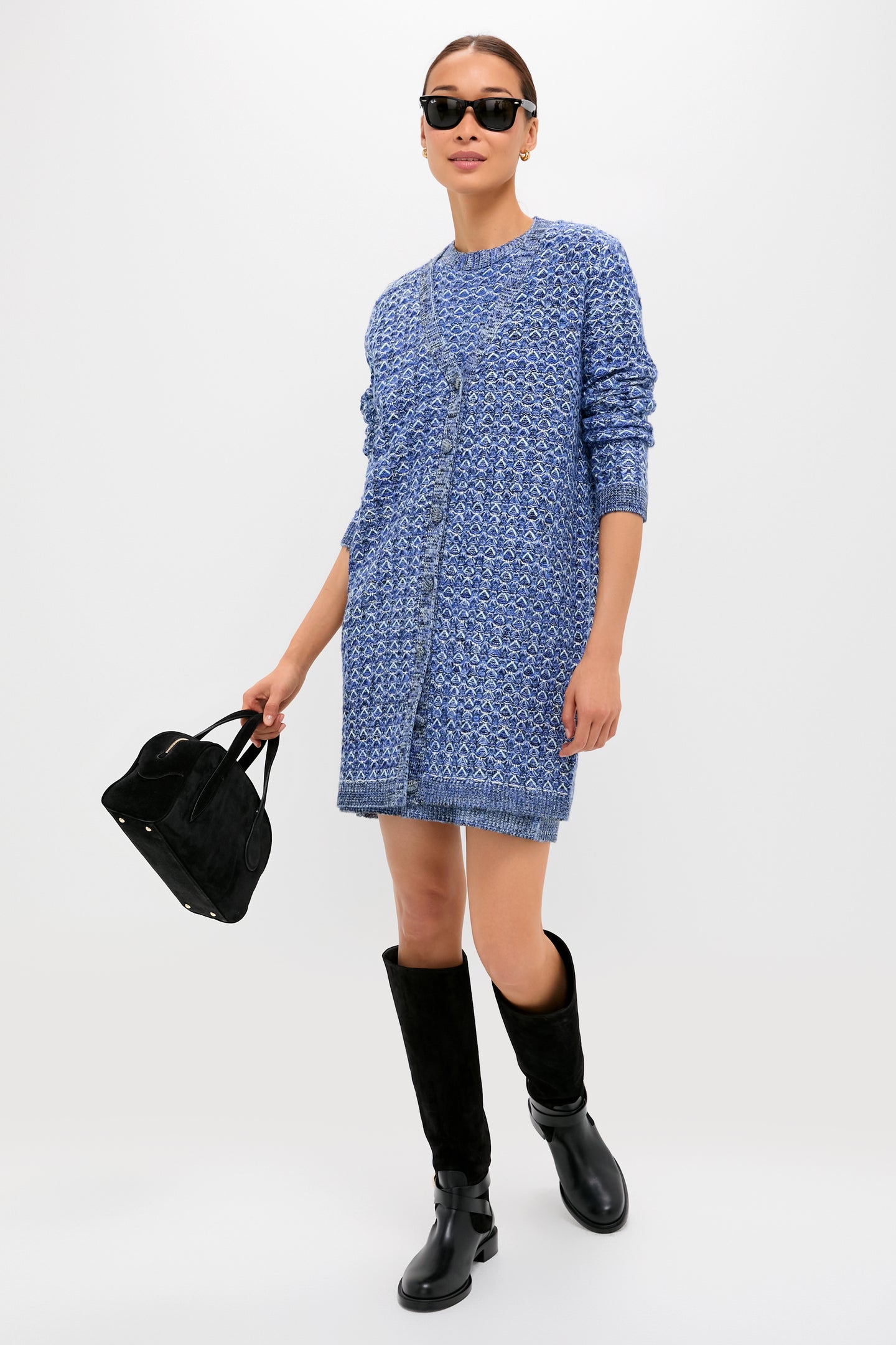 A woman models a Tuckernuck blue knit dress with black knee-high boots, a black handbag, and sunglasses against a white background. The dress’s mid-weight knit ensures comfort and style for any occasion.