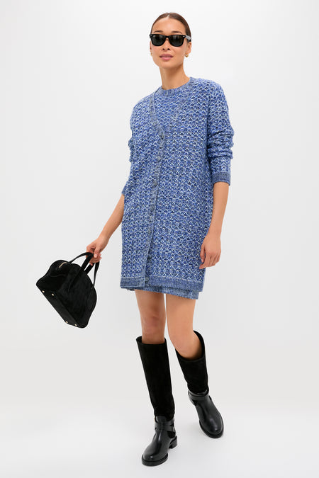 A woman models a Tuckernuck blue knit dress with black knee-high boots, a black handbag, and sunglasses against a white background. The dress’s mid-weight knit ensures comfort and style for any occasion.