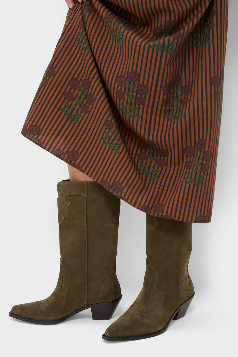 Woman wearing classic Dark Olive Suede Wilson Cowboy Boots with pointed toe and block heel, styled with a floral skirt, embodying effortless, fun, high-end Western charm.
