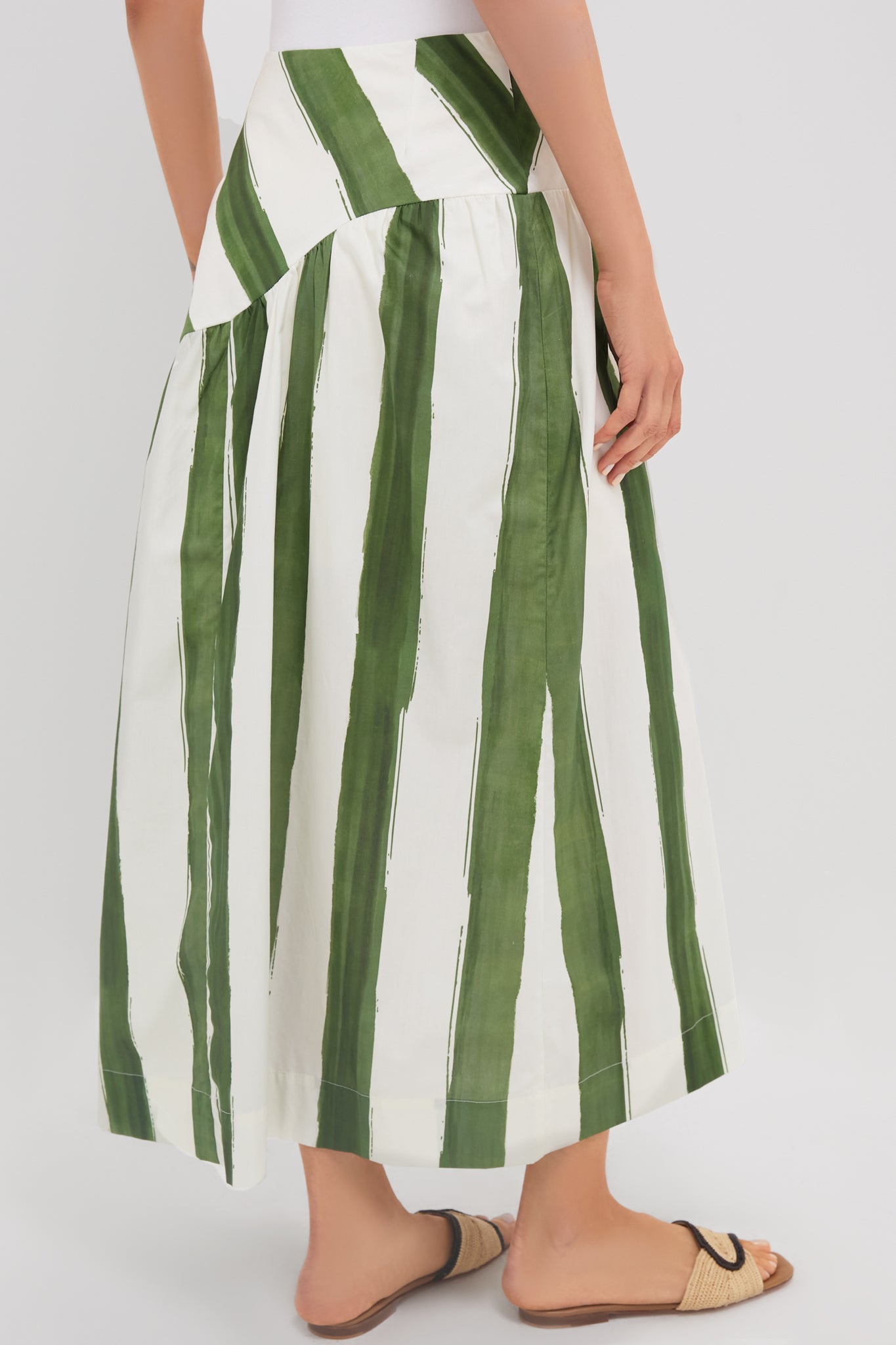 Green Stripe Nature Midi Skirt features a classic drop waist and effortless A-line silhouette, paired with woven-straw sandals for a fun, high-end look.