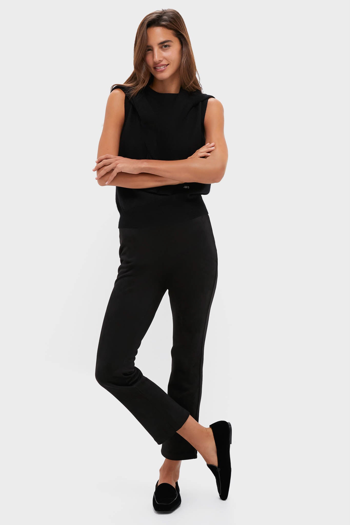 A woman wears a cashmere vest, black pants, and black slip-on shoes.