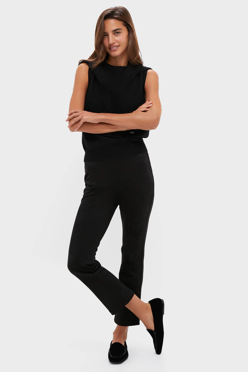 A woman wears a cashmere vest, black pants, and black slip-on shoes.