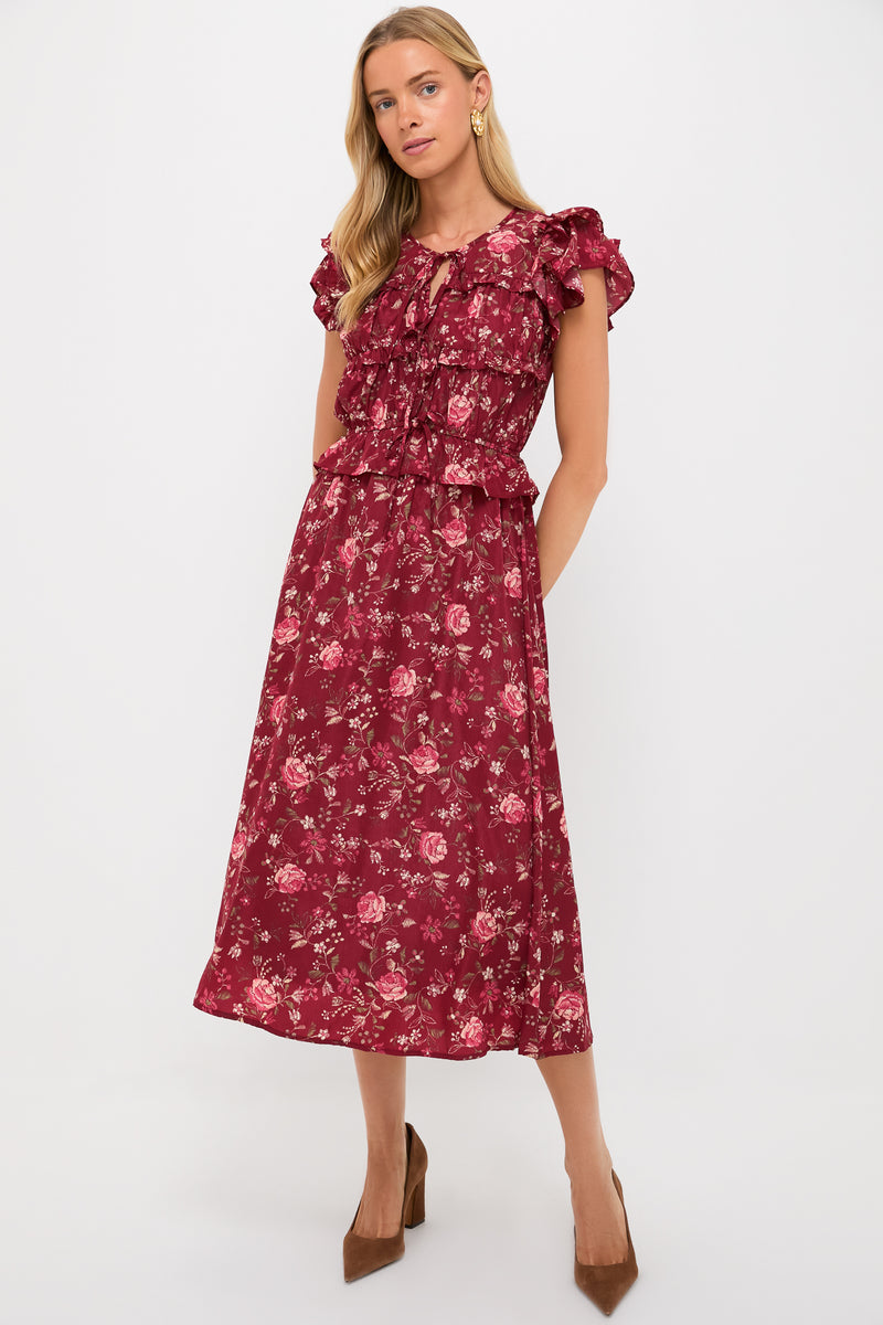 A woman wears a Moon River maroon floral midi dress featuring ruffle sleeves and an elastic waist, paired with brown heels.