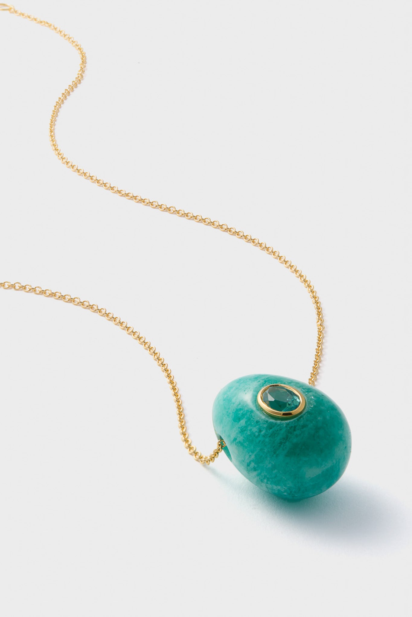 The Lizzie Fortunato necklace features gold plating, an amazonite chain, a large turquoise stone pendant, and a small circular gemstone set in a gold bezel on the main stone.