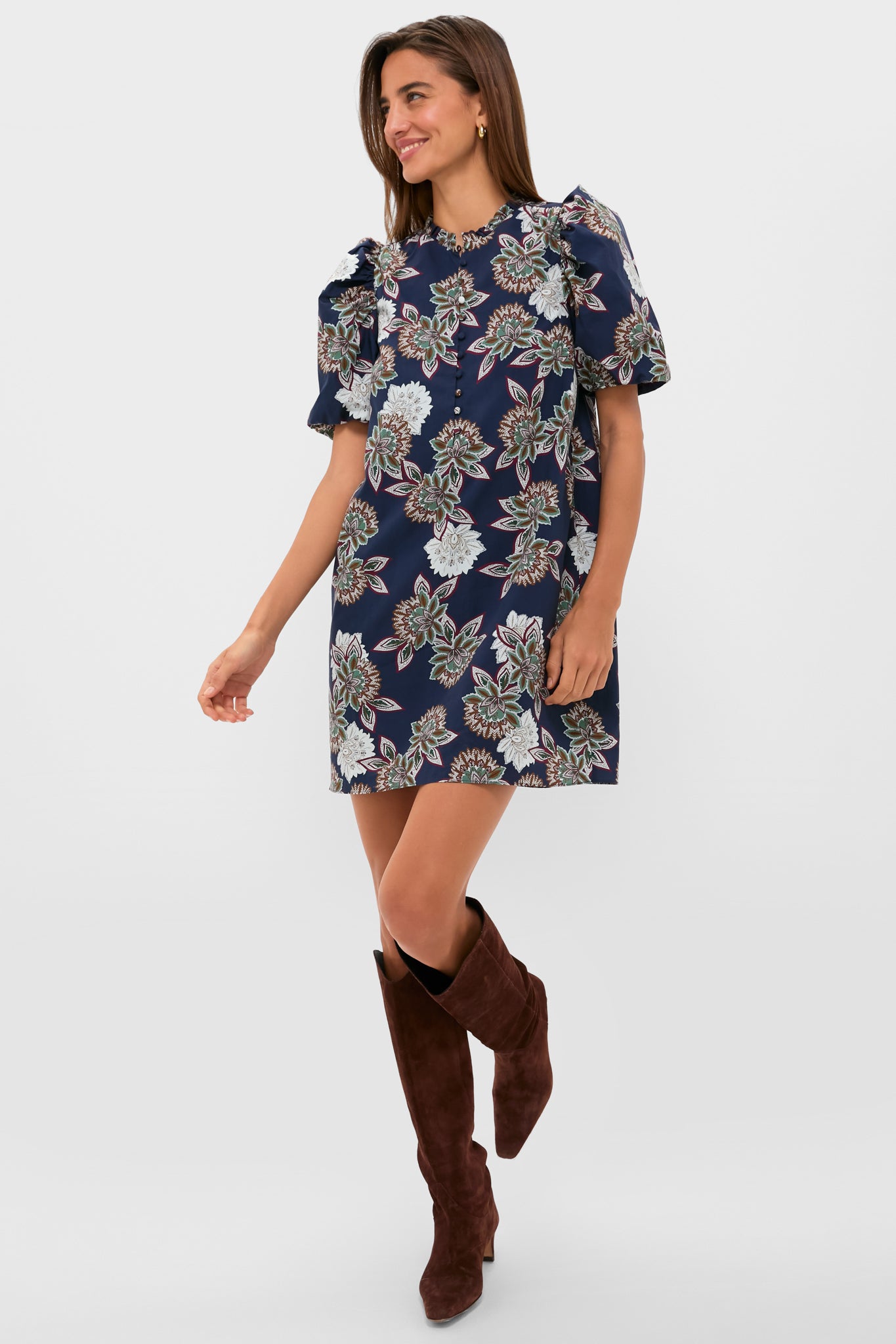 Young woman models the classic Navy Floral Mimi Mini Dress with puff sleeves, ruffle collar, and suede boots, embodying an effortless, high-end, and fun style.