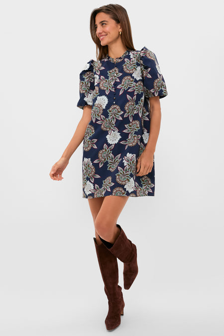 Young woman models the classic Navy Floral Mimi Mini Dress with puff sleeves, ruffle collar, and suede boots, embodying an effortless, high-end, and fun style.