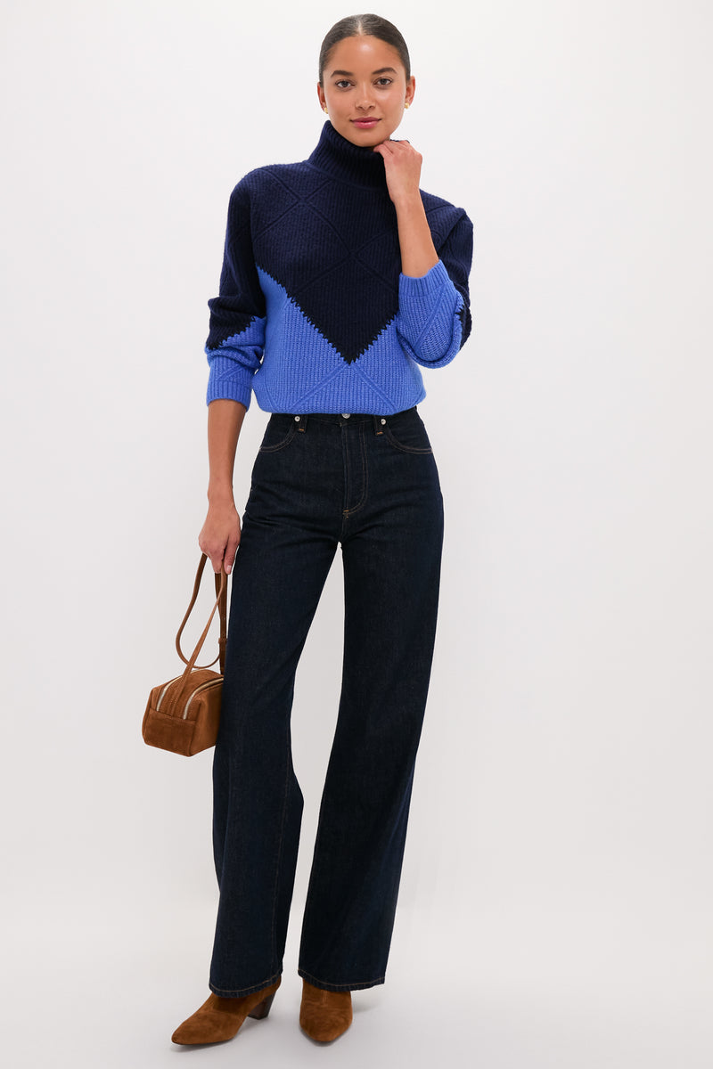 Woman models Navy & Cerulean Diamond Demi Turtleneck, a classic yet fun, high-end sweater paired with dark-indigo wide-leg jeans and brown suede accessories for an effortless look.