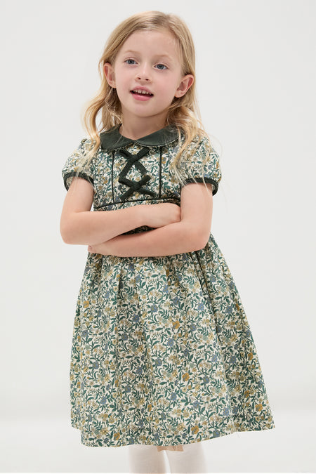 Young girl models the classic, high-end Bottle Green Floral Portia Girl Dress featuring an effortless fit-and-flare silhouette, Peter Pan collar, and short puffed sleeves.