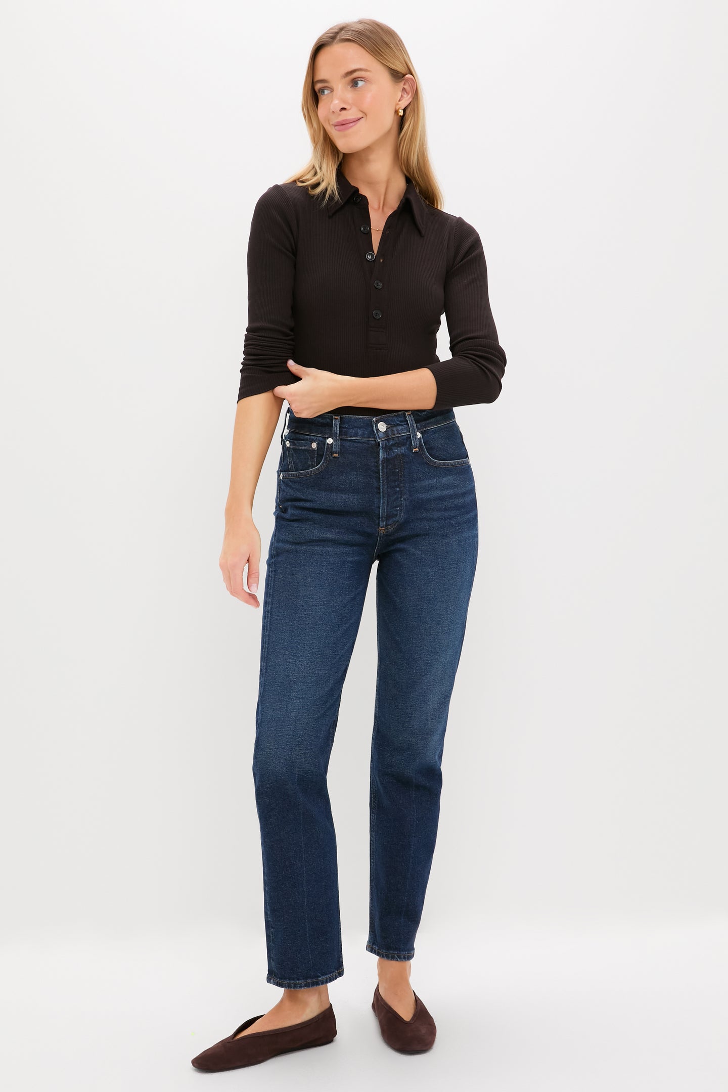Model wearing Sutherland Blaine Jean, a classic high-rise, straight-leg denim with a vintage-inspired, effortless look. Paired with a black ribbed top and brown slip-on shoes.