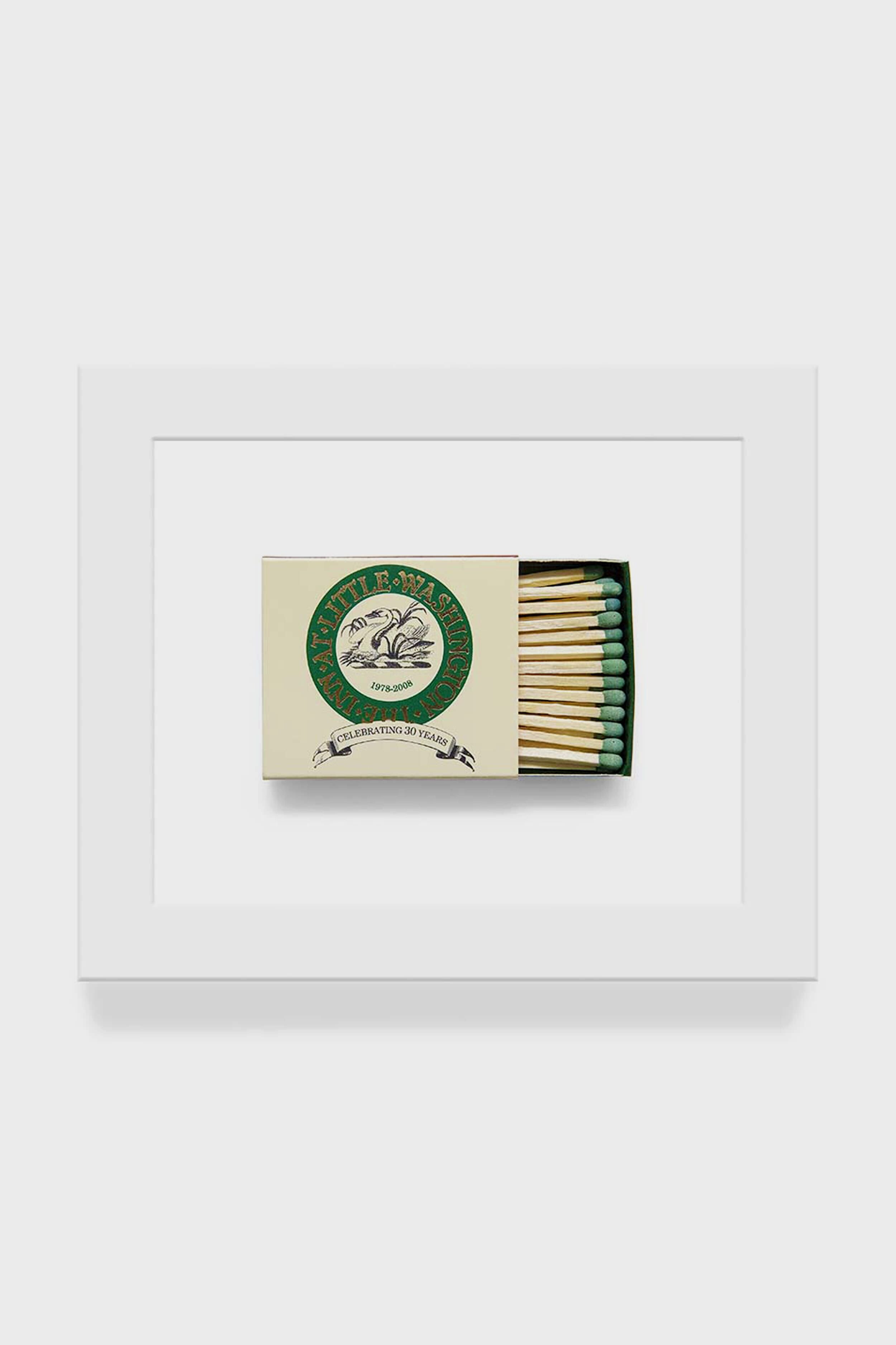 A partially open box of green-tipped matches reveals several sticks inside; the box displays a circular logo and Matchbook Diaries by Charles Ryan Clarke branding, shown in detailed macro photography.