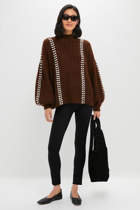 Woman in oversized Brown Mayu Sweater with chic mock neck and embroidered trim, paired with leggings and ballet flats, holding a slouchy black tote. Effortless and high-end style.