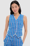 A woman stands with hands in pockets, wearing a CeliaB blue plaid vest and matching pants, paired with a sleeveless nautical vest top from CeliaB.
