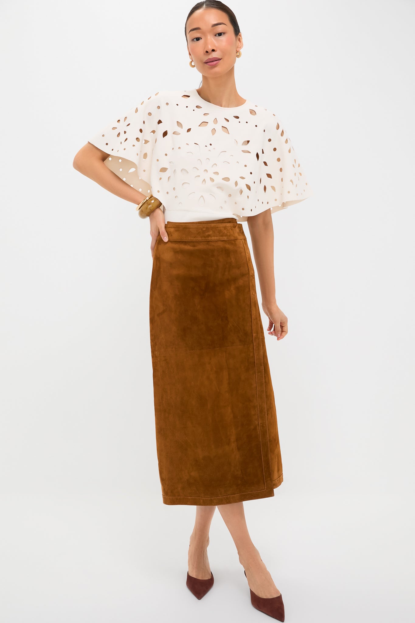 Woman models Nutmeg Winona Skirt, a classic, high-end suede piece with a wrap design. Effortlessly paired with a loose blouse and heels for a fun, sophisticated look.