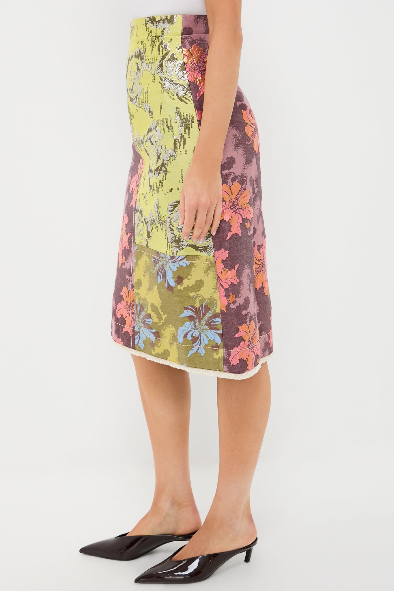 A person wears the Alemais Multi Adriana Jacquard Midi Skirt, showcasing vibrant floral patterns and patchwork details, styled with black heeled mules.