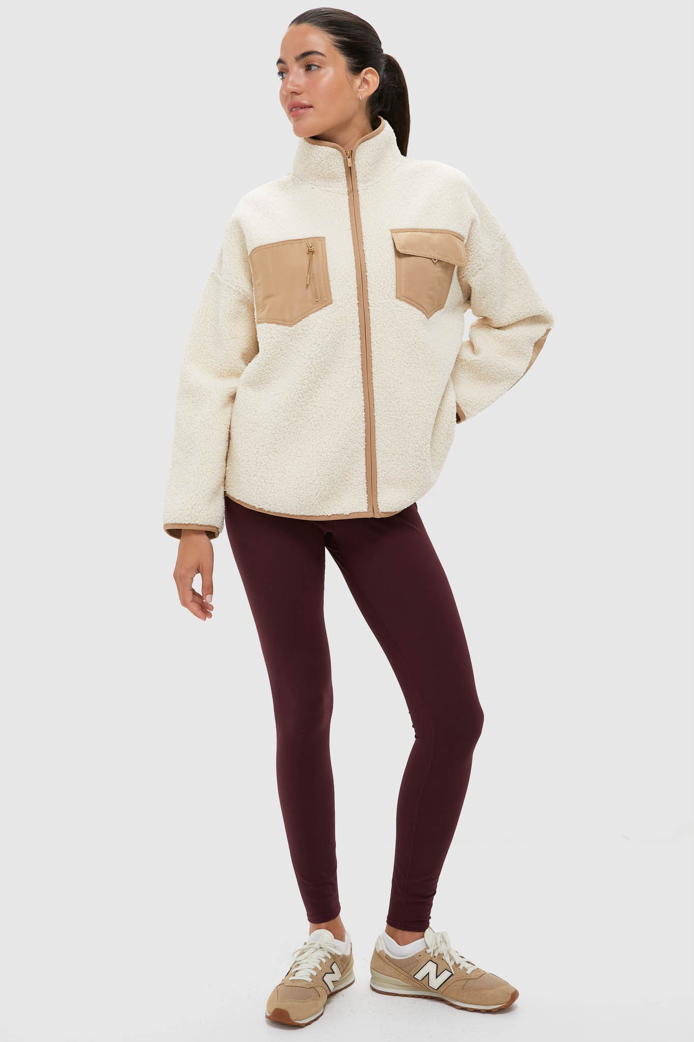 Model in Buttercream Fleece Lawrence Full Length Zip Up, showcasing an effortless, classic style with burgundy leggings and tan-white sneakers, epitomizing cool, high-end, fun fashion.