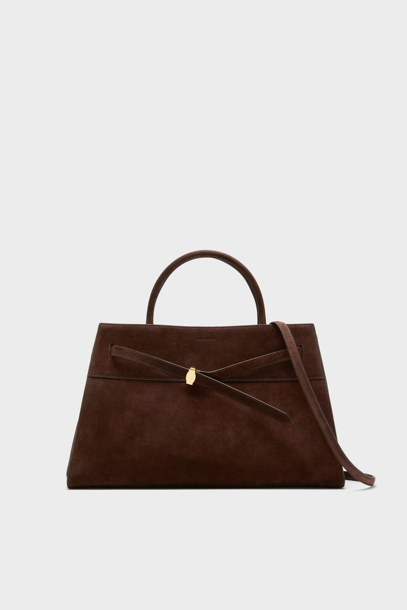 A Veronica Beard brown Italian suede bag with a top handle, gold clasp, and removable shoulder strap is shown against a plain, light background.