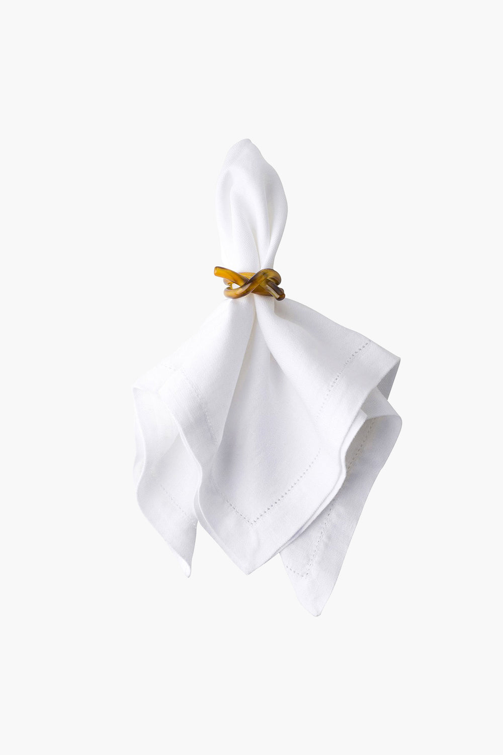 A white cloth napkin is held by a Juliska amber napkin ring, adding a touch of elegance and charm.