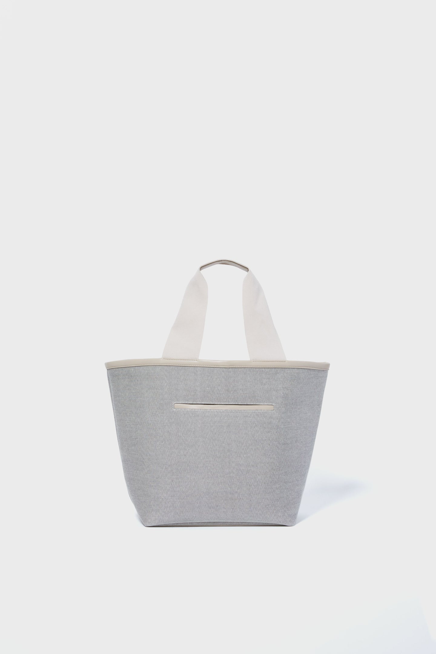 The Tuckernuck Accessories tote is a medium-sized, light gray marled bag with wide off-white handles and a small front pocket—ideal for carrying your essentials in style.