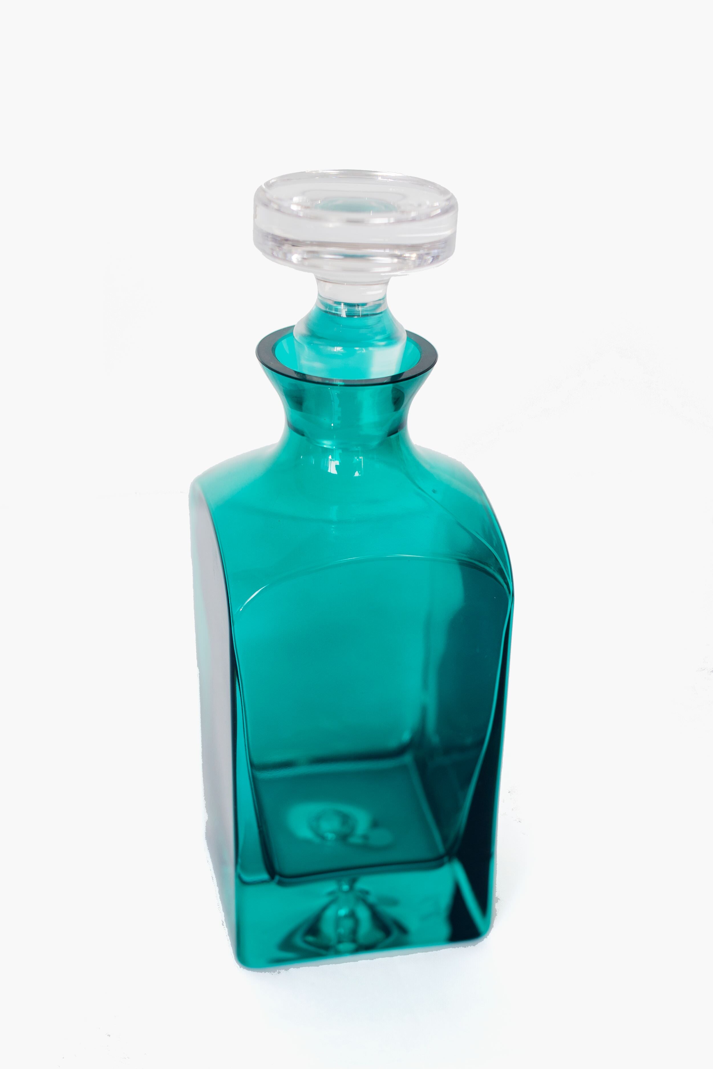 The Estelle Colored Glass square-shaped emerald decanter is crafted from hand-blown colored glass by skilled artisans in Poland and features a clear, round stopper.