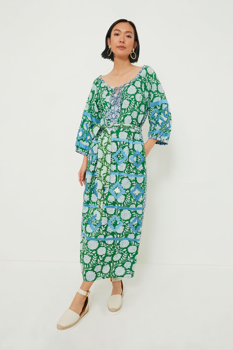 A woman wears a long, green and blue floral block print dress with 3/4 sleeves by KLEED and white espadrille sandals, styled as sustainable loungewear.