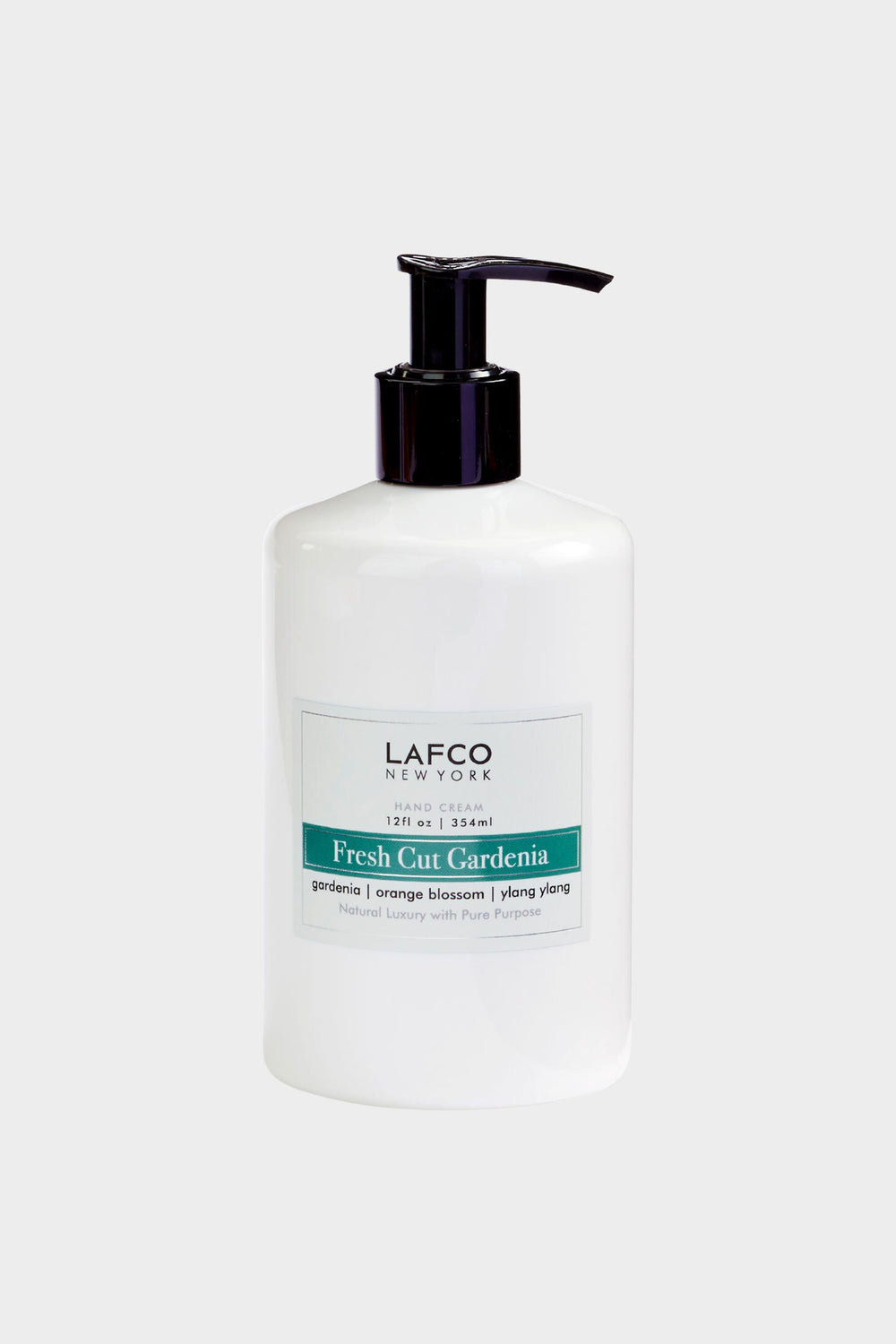 A white LAFCO New York Hand Cream pump bottle, Fresh Cut Gardenia scent (gardenia, orange blossom, ylang ylang, 12 fl oz/354 ml), sits next to luxury candles and non-toxic soy candles.