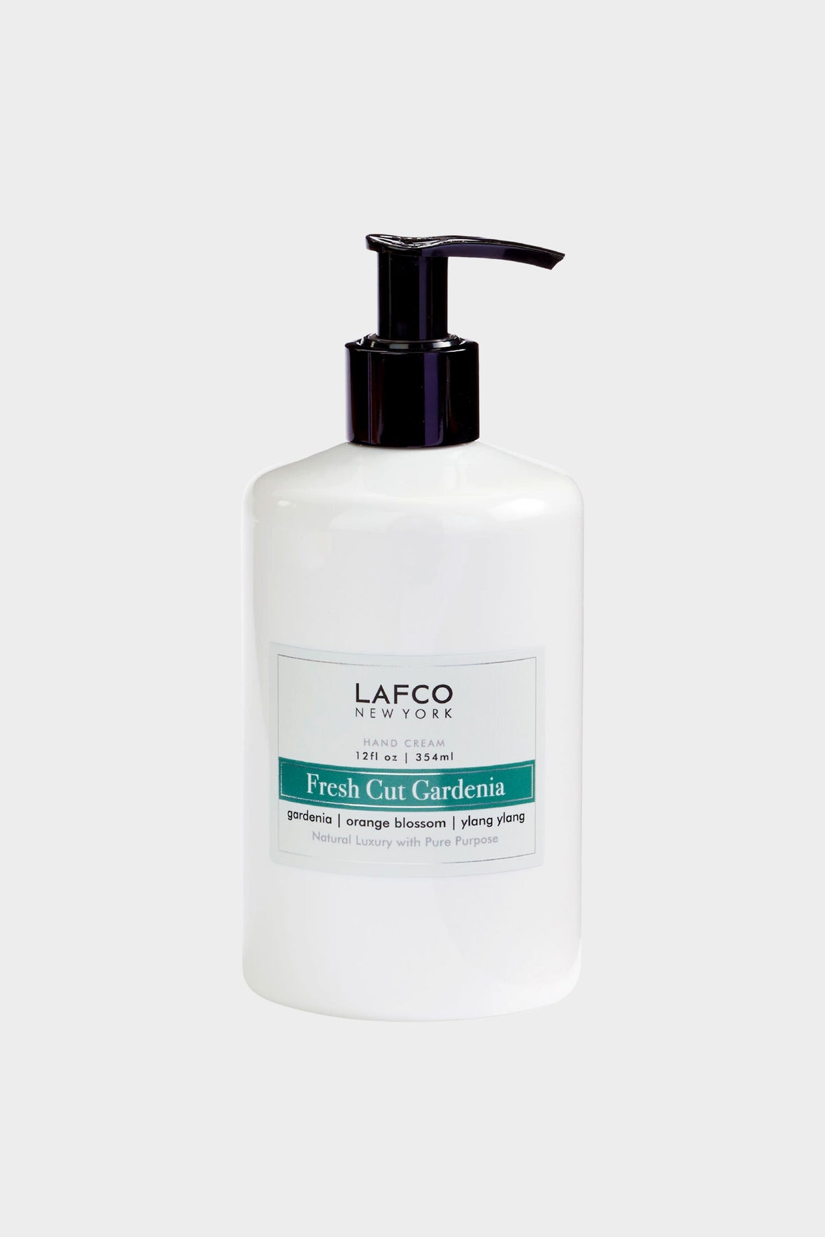 A white LAFCO New York Hand Cream pump bottle, Fresh Cut Gardenia scent (gardenia, orange blossom, ylang ylang, 12 fl oz/354 ml), sits next to luxury candles and non-toxic soy candles.