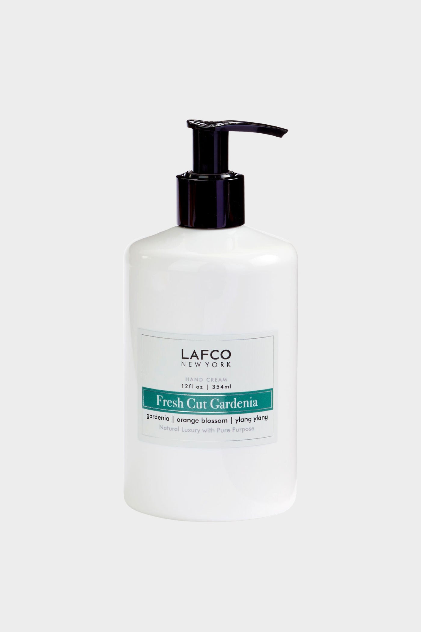 A white LAFCO New York Hand Cream pump bottle, Fresh Cut Gardenia scent (gardenia, orange blossom, ylang ylang, 12 fl oz/354 ml), sits next to luxury candles and non-toxic soy candles.