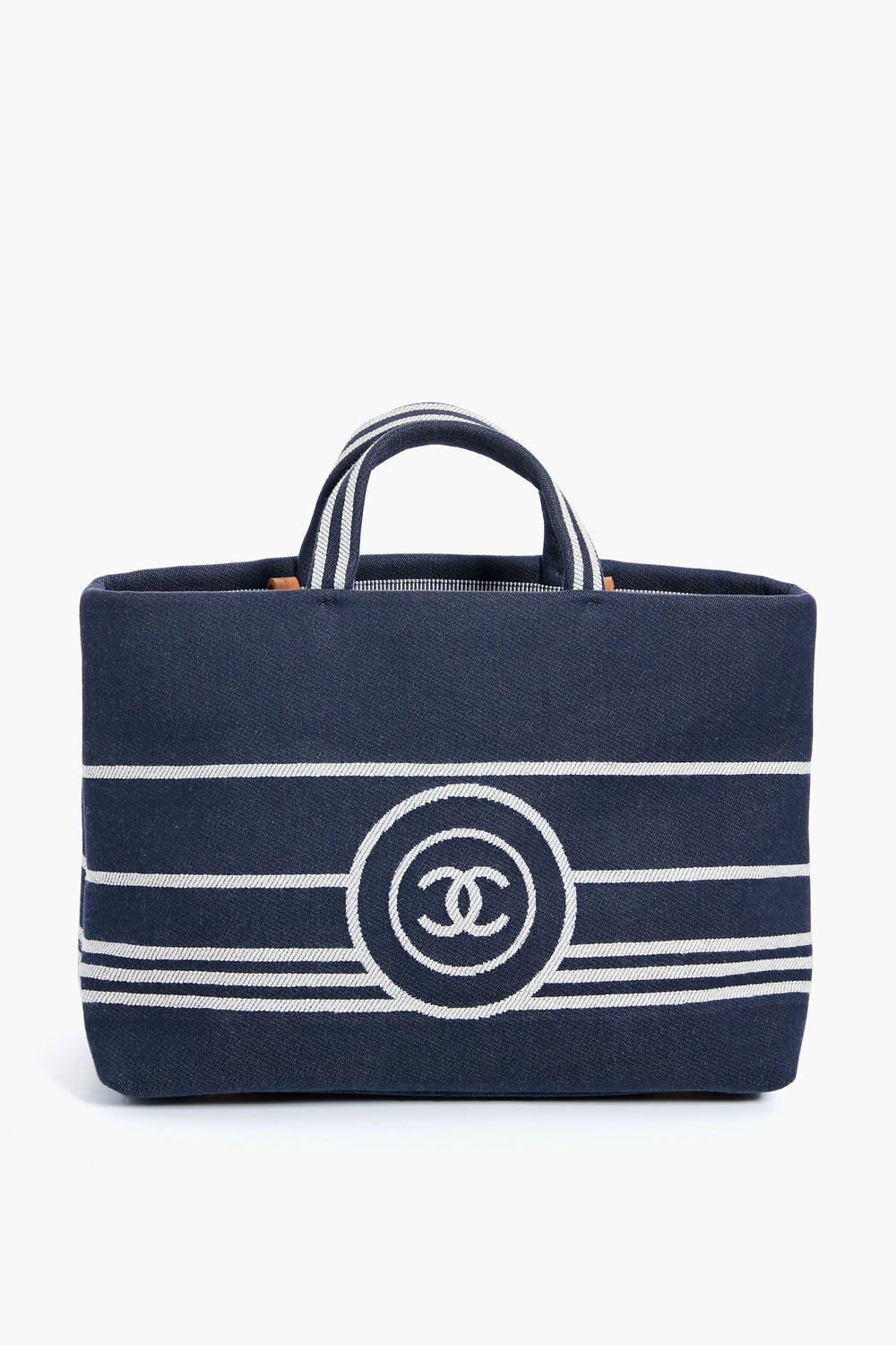 A navy blue luxury handbag with white horizontal stripes, two short handles, and a bold front logo from the Tuckernuck Archive Collection, inspired by the Chanel Denim Canvas Border Tote.