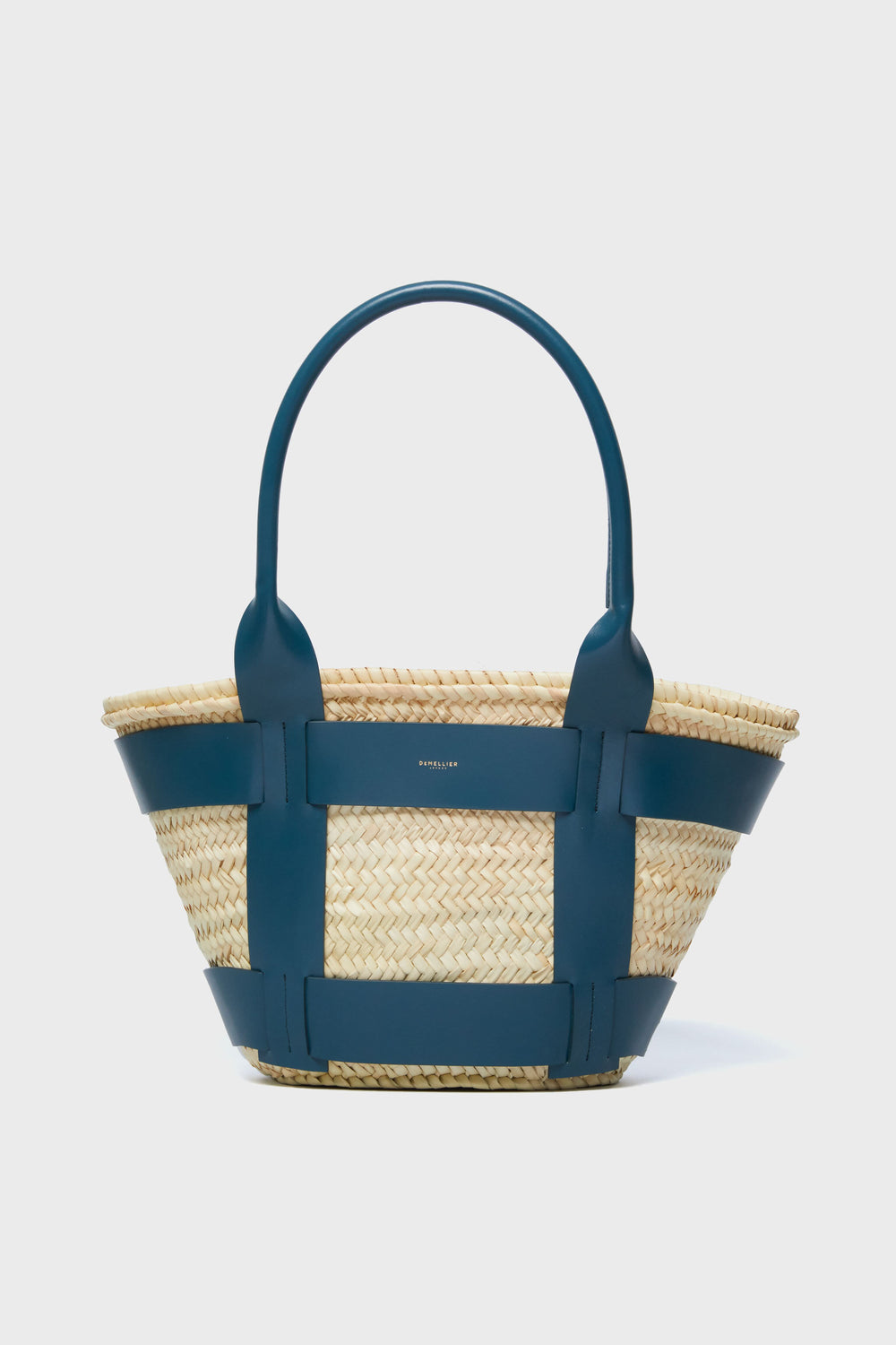 The Demellier woven raffia bag features wide dark blue leather handles and trim—an ideal choice to elevate your collection of handcrafted handbags and luxury accessories.