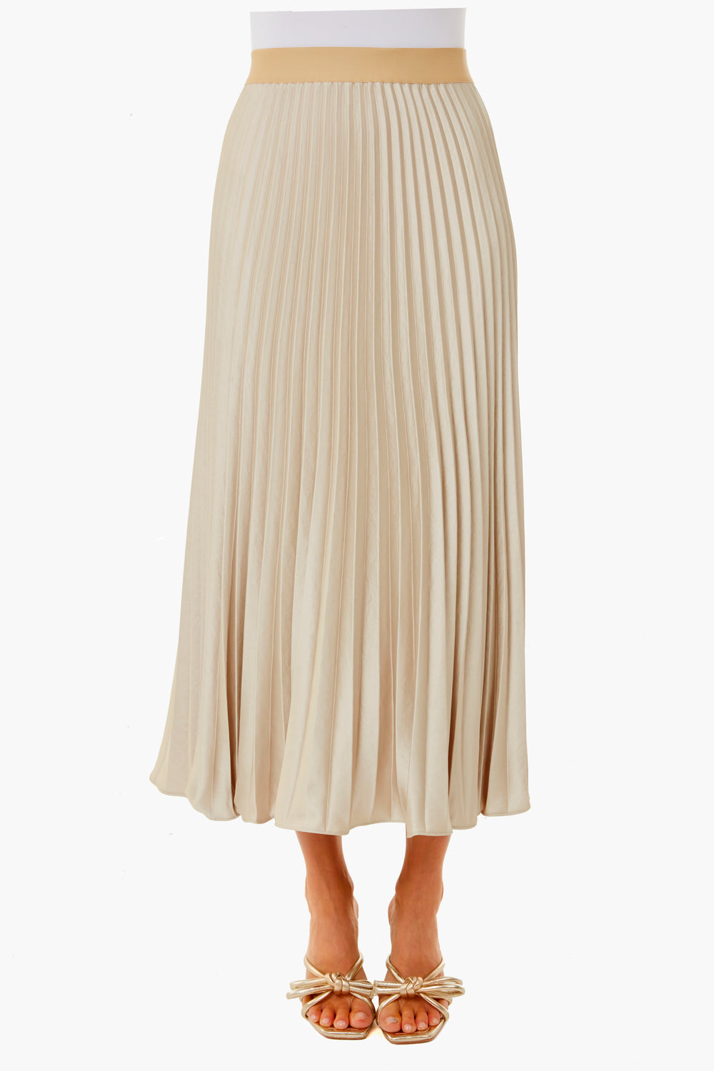 A person wears a beige pleated midi skirt from Weekend Max Mara with beige open-toe sandals decorated with bows.