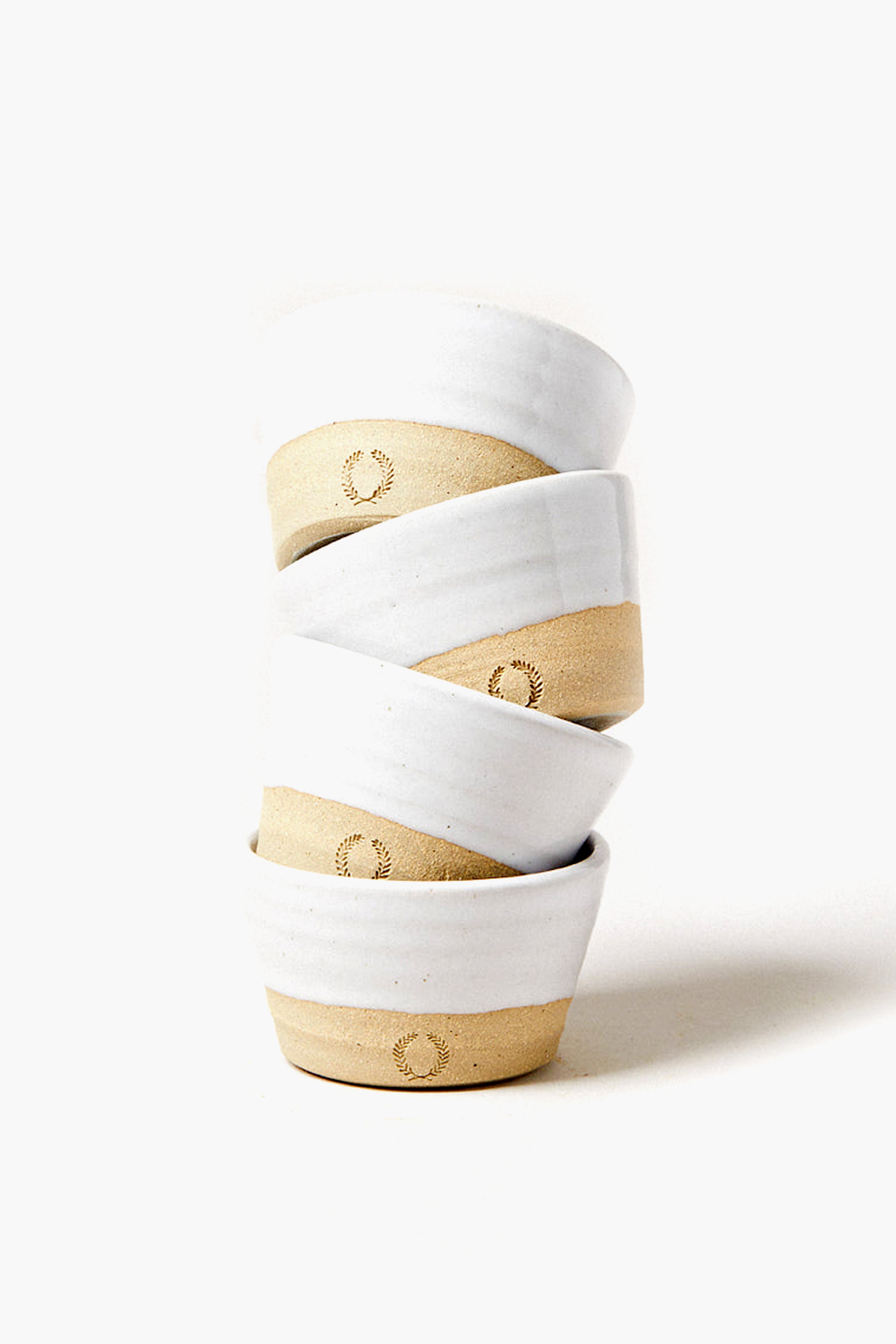 Four stacked ceramic Petite Silo Bowls by Farmhouse Pottery, Inc feature white glazed tops and unglazed beige bottoms, adding classic American Stoneware charm to your table.