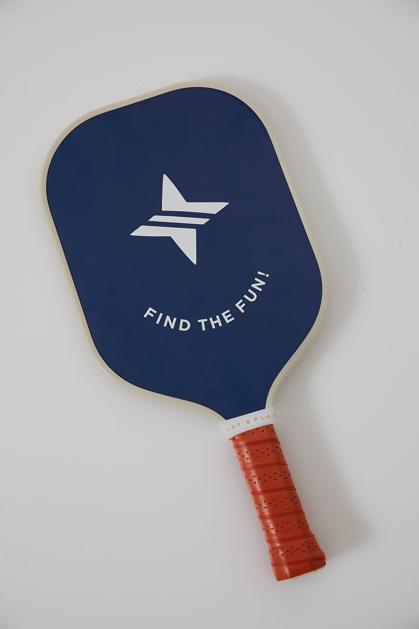 A blue Tnuck Sport x Recess Pickleball paddle with a fiberglass surface, honeycomb core, white geometric logo, "FIND THE FUN!" text, and red grip rests on a white surface.