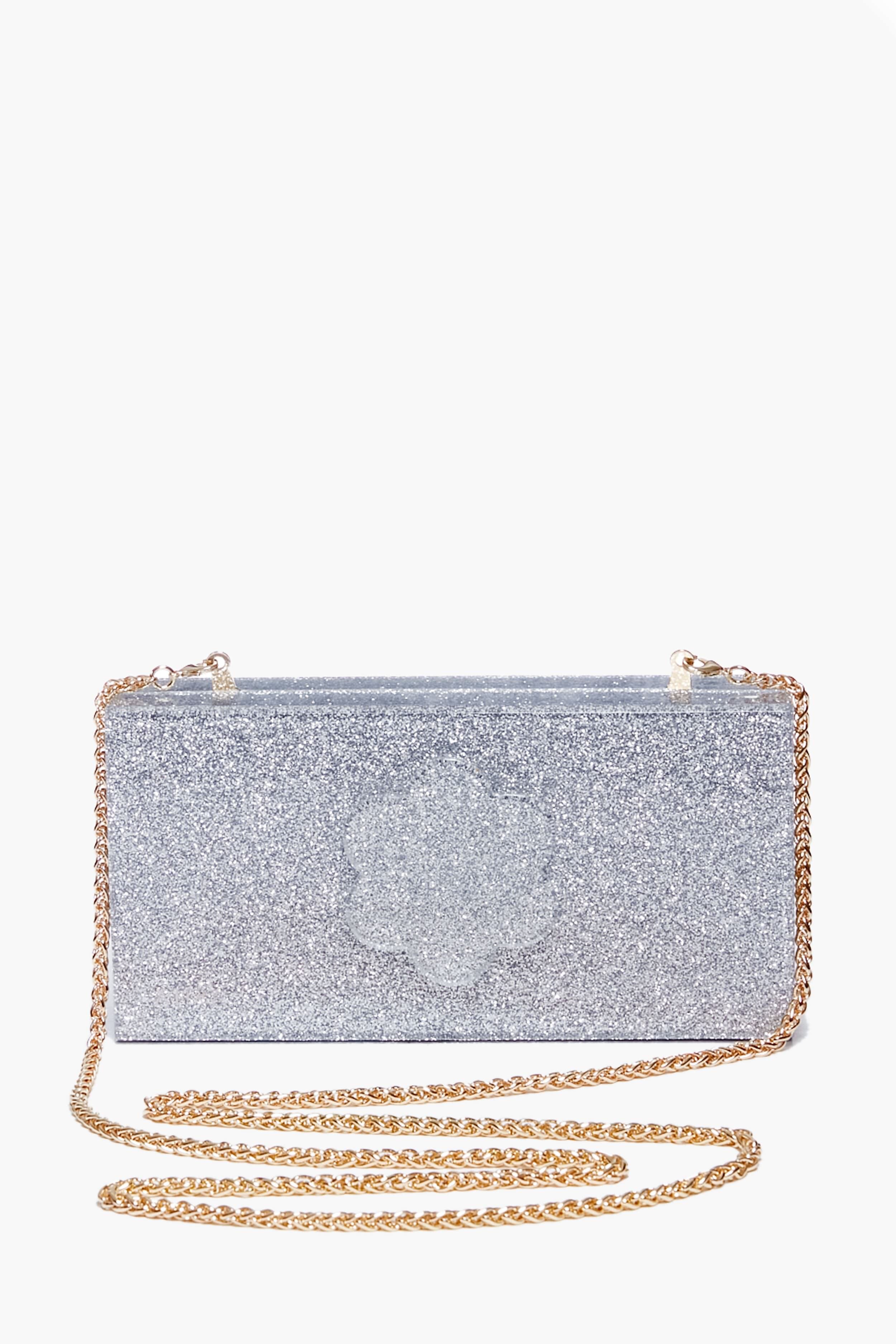 The ASHA Silver Sparkle Flower Clutch is a rectangular bag with a gold chain strap, dazzling glitter, and floral accents.