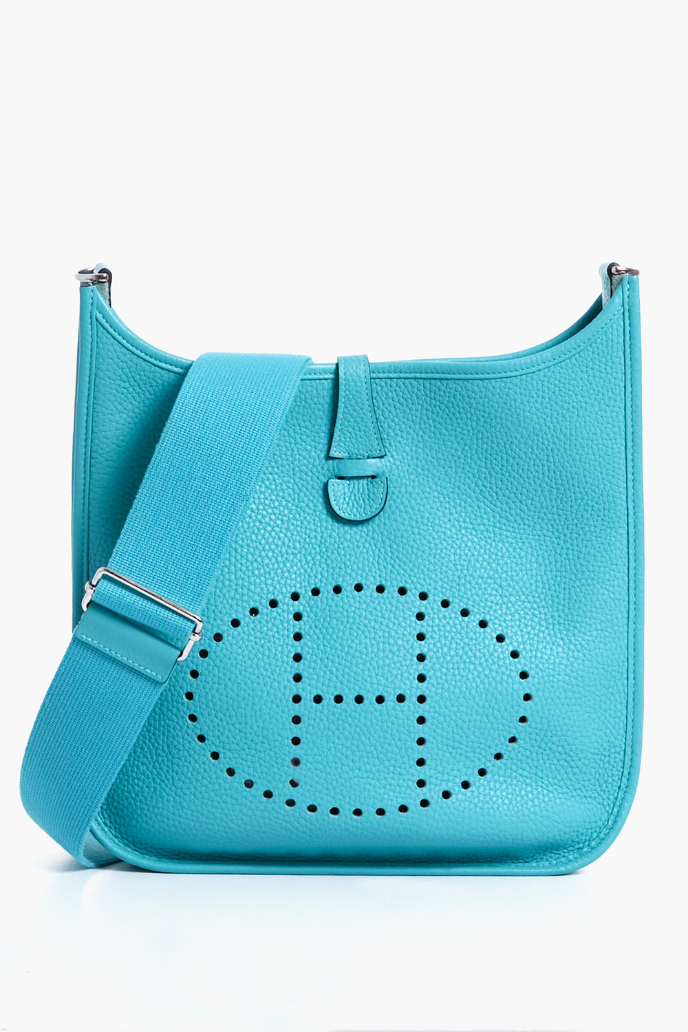 A turquoise leather shoulder bag from the Tuckernuck Archive Collection with a wide strap and a perforated oval design featuring the letter H on the front, inspired by Hermès luxury bags.